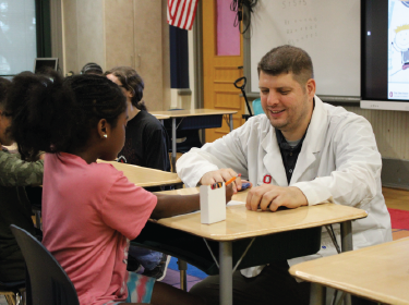 man in white doctor coat tutoring student sitting in desk